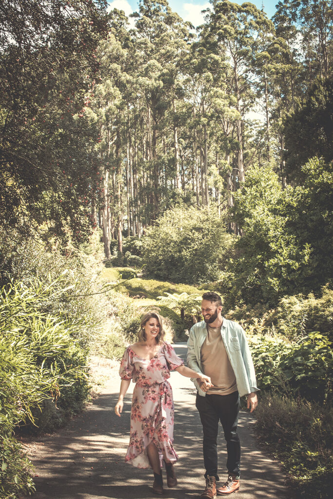 couple holding hands walking in a park in Mt Dandenong at an engagement session.