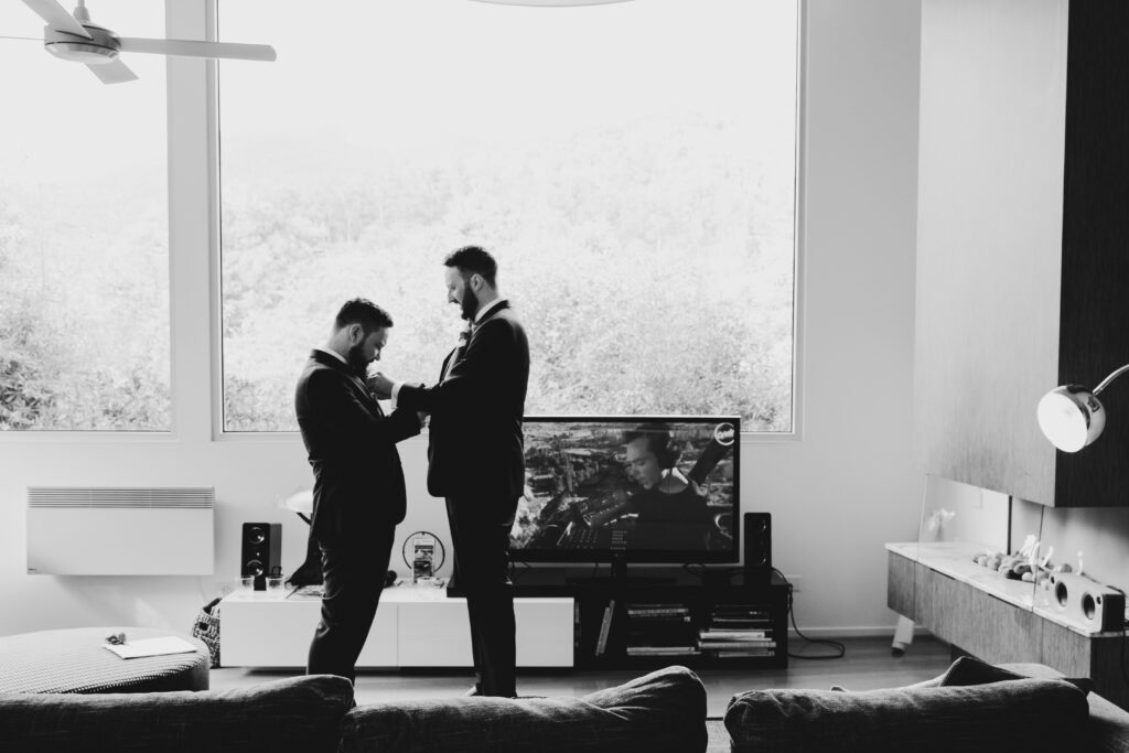 groom and best man in a black and white image helping each other do cufflinks, mat and sarah used my tips on how to plan a wedding timeline