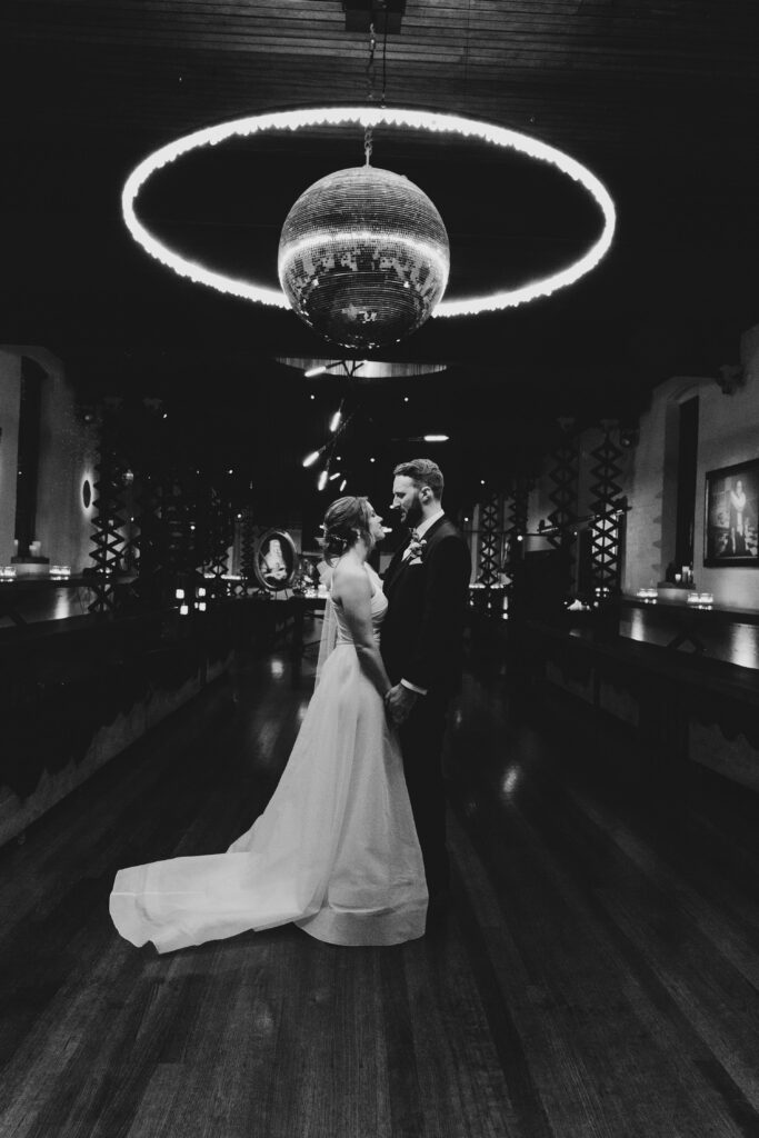 black and white photo of bride and groom dancing under a disco ball at Projekt 3488 in winter