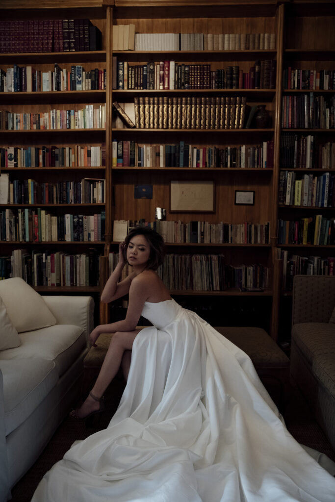 Image of a bride sitting ina gorgeous white gown in a library