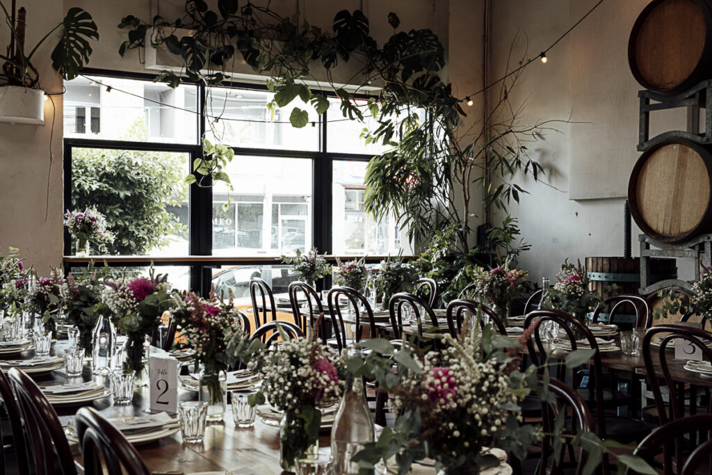 Colour image of tables and chairs fustooned with flowers and indoor plants at Noisy Ritual