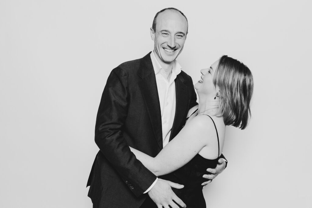 A black and white photo of a couple dressed in formal wear having fun and having a photo taken