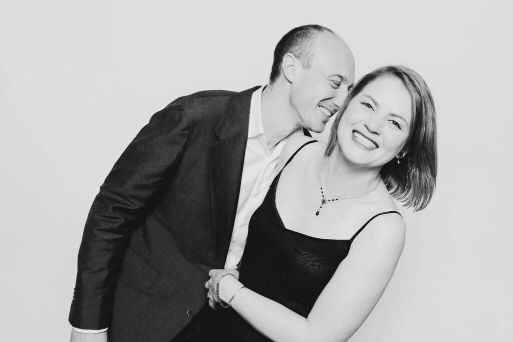 A black and white photo of a couple dressed in formal wear having fun and having a photo taken