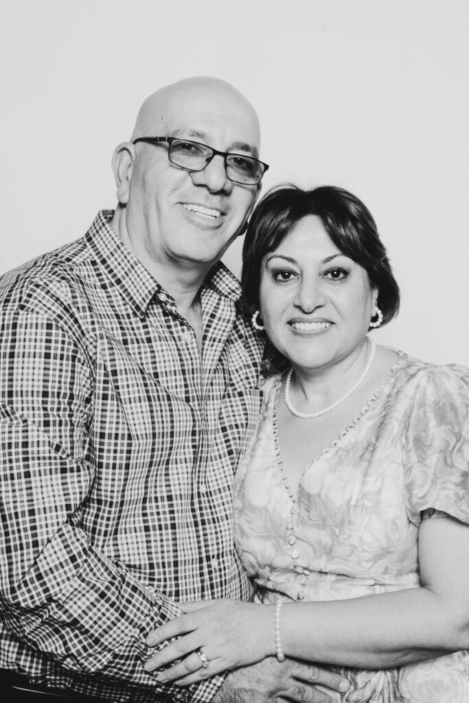 A black and white photo of an older couple standing in a portrait studio haveing a picture taken