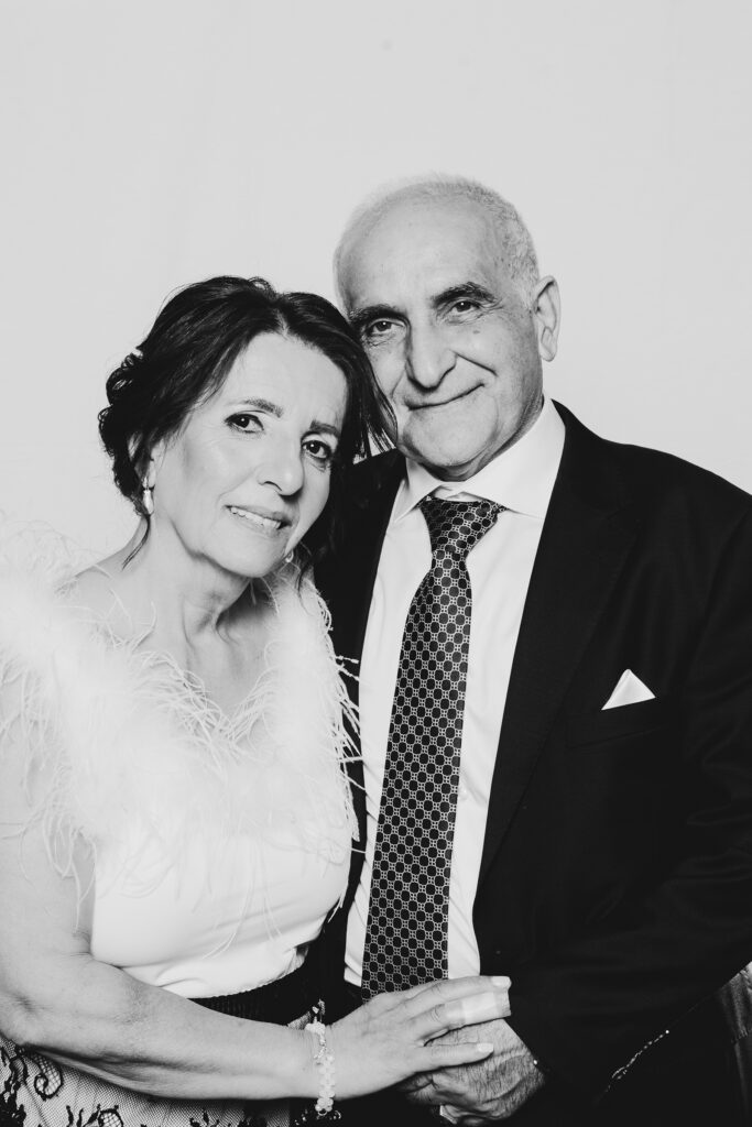 A black and white photo of an older couple standing in a portrait studio haveing a picture taken