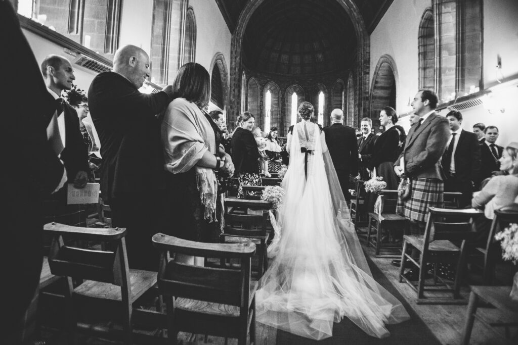 black and white image of a bride walking down the aisle with her dad in a chuirch in Scotland