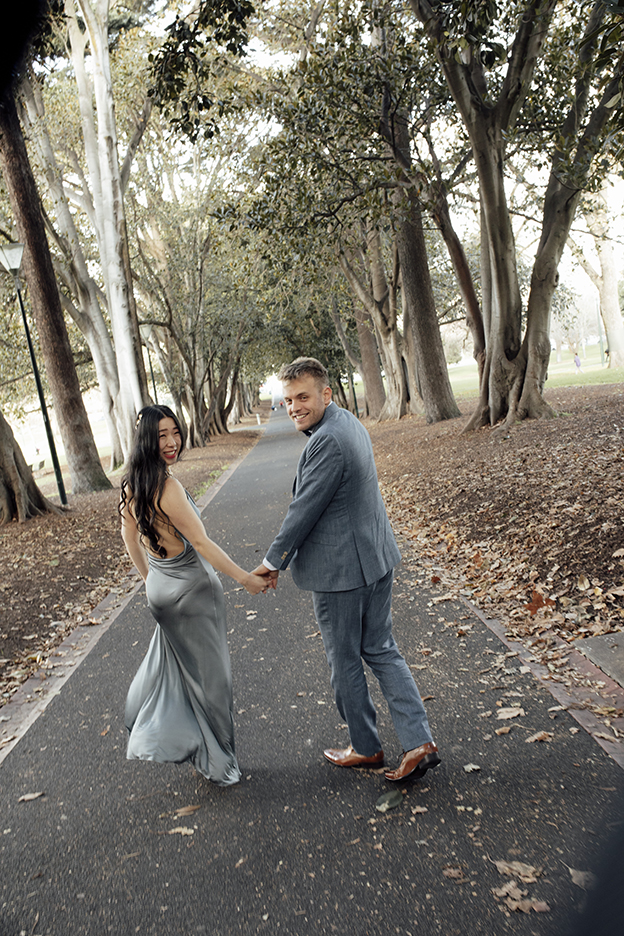 A couple walking hand in hand in treasury gardens smiling and laughing having a wedding photos taken