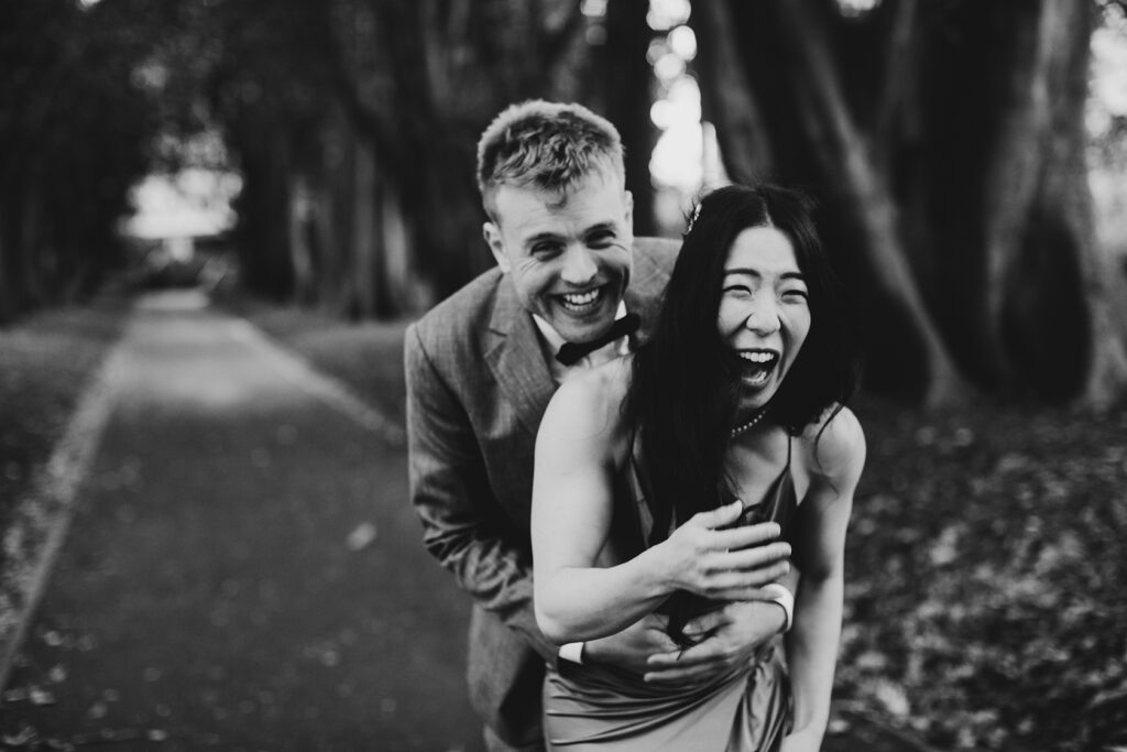 A couple walking hand in hand in treasury gardens smiling and laughing having a wedding photos taken