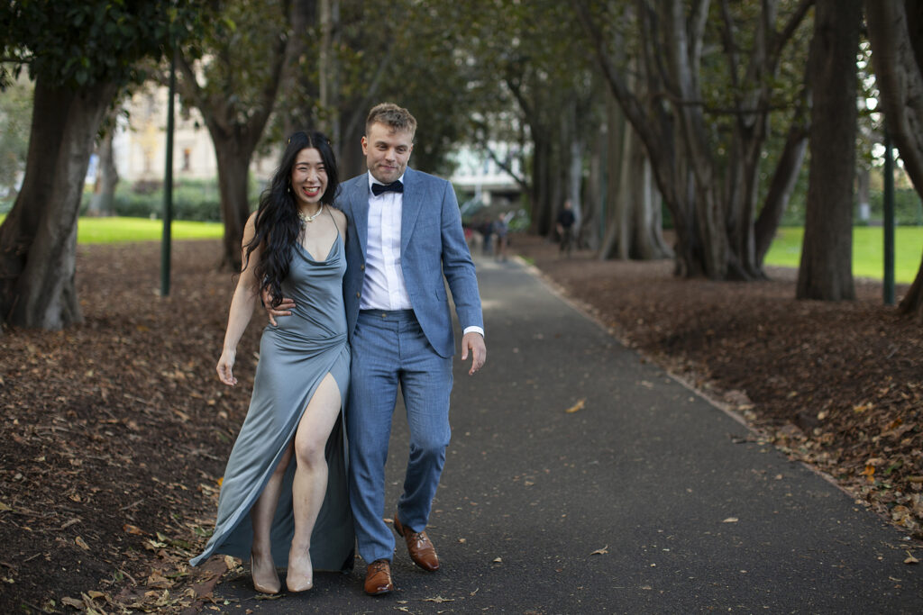 A couple walking hand in hand in treasury gardens smiling and laughing having a wedding photos taken