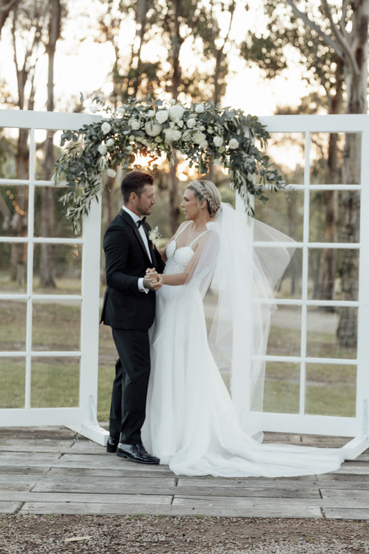 A colour image of a bride and groom having professional wedding photos taken at eight acres lakes entrance on their wedding day.