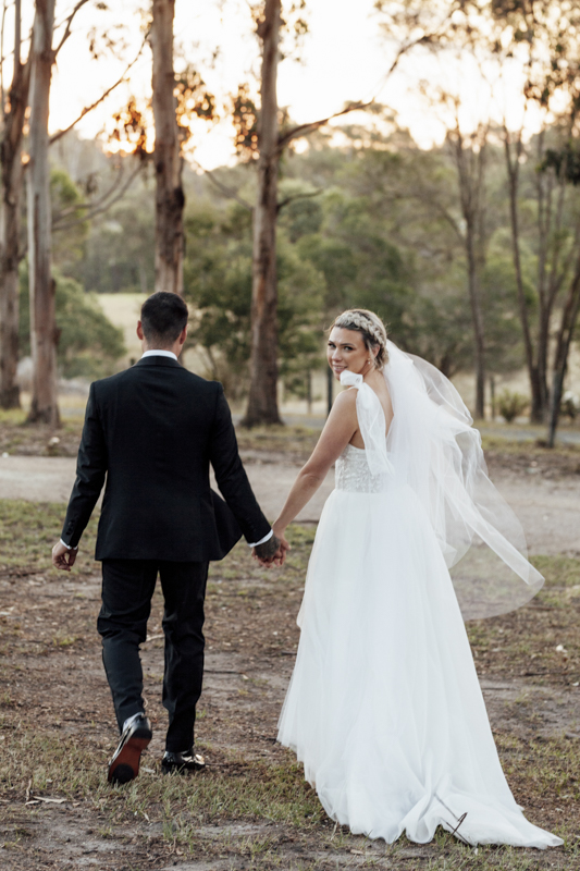 A colour image of a bride and groom having professional wedding photos taken at eight acres lakes entrance on their wedding day.