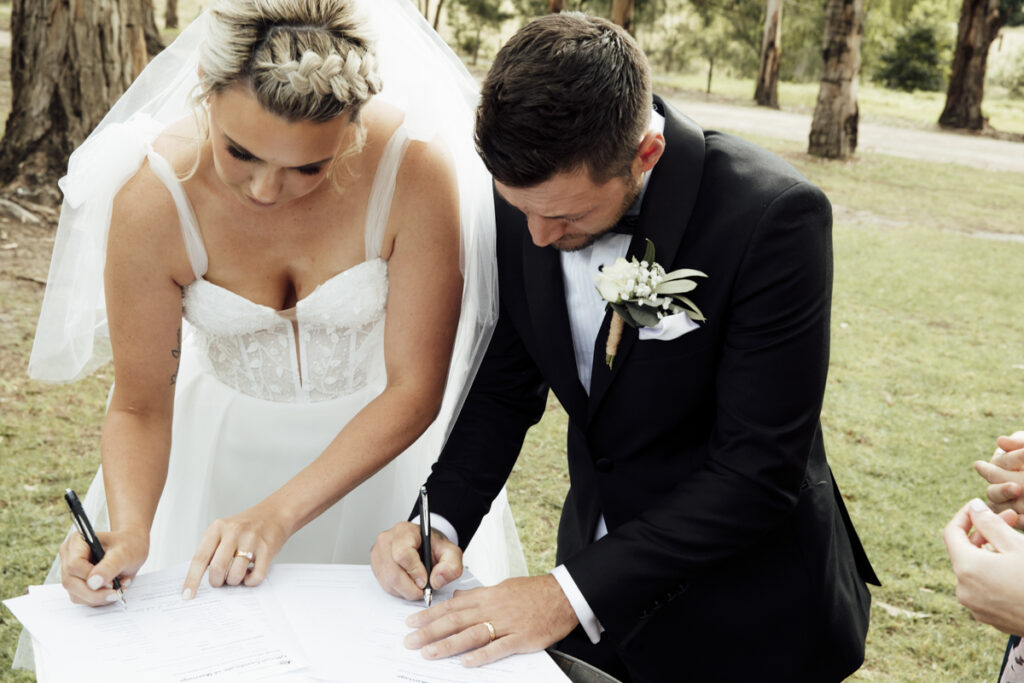 Acolour image of a bride and groom signing the registry