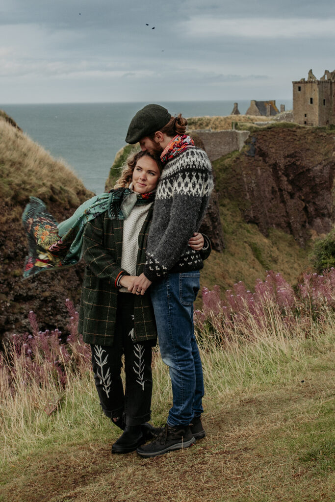 A couple having photos taken at Dunnotter Castle in Scotland. She is wearing an origional Helen Ruth Scarf