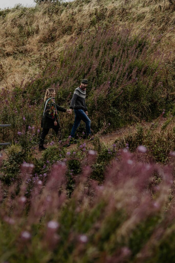 A couple having wedding photos taken near Aberdeen, at Dunnotter castle in Scotland. They are walking through the flowery fields.