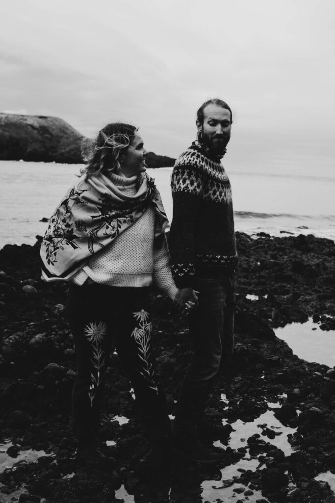 A couple having black and white photos taken at Dunnotter Castle in Scotland. She is wearing an original Helen Ruth Scarf