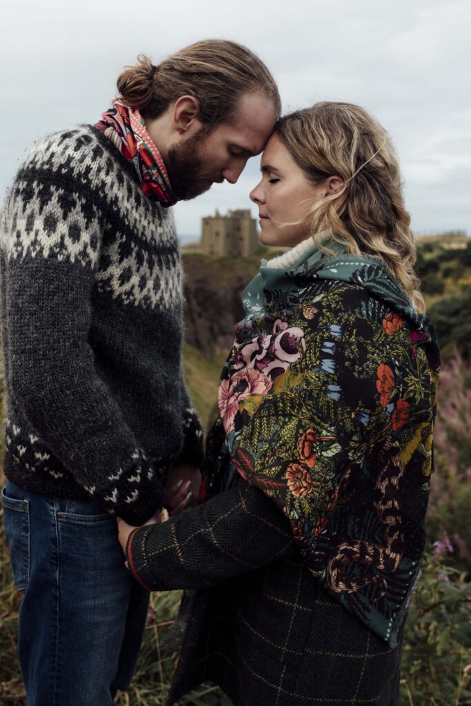 A couple having photos taken at Dunnotter Castle in Scotland. She is wearing an original Helen Ruth Scarf