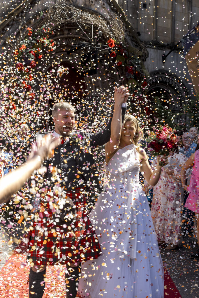 Edinburgh wedding photographer candid, a bride and groomcoming out to a wall of confetti at the Ghillie Dhu
