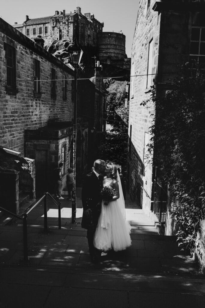 Edinburgh wedding photographer candid, a bride and groom standing on the Vennel steps having wedding photos.