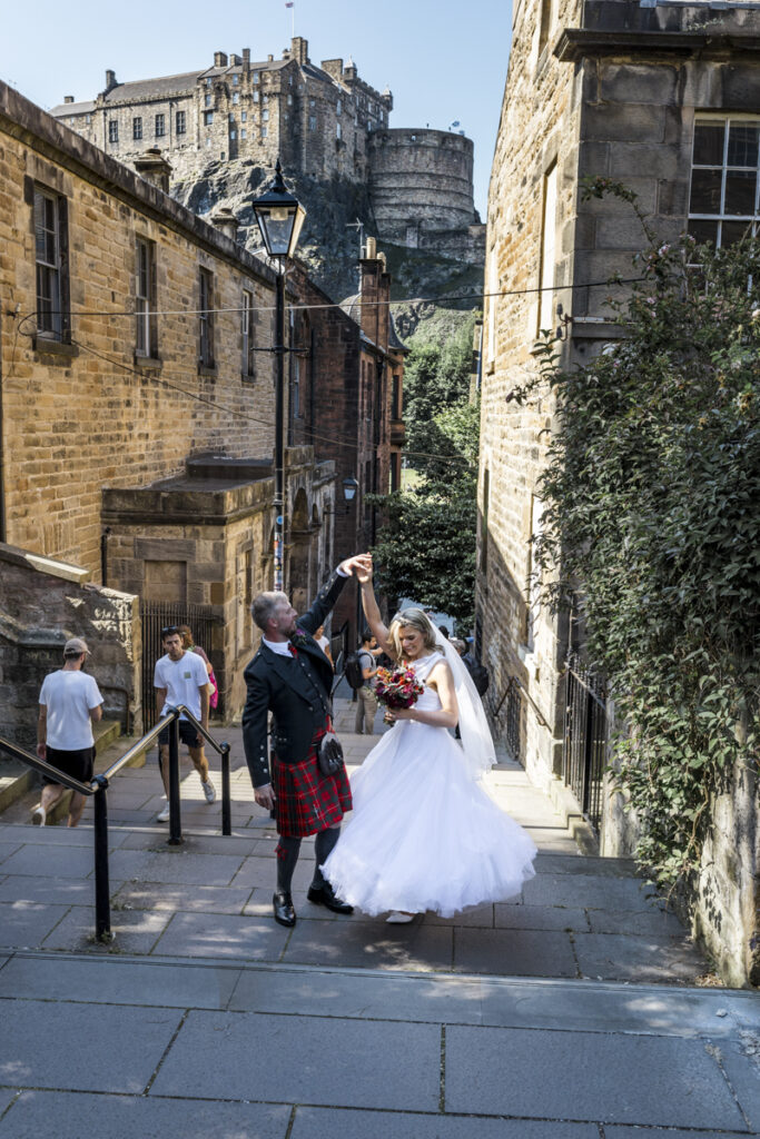 Edinburgh wedding photographer candid, a bride and groom standing on the Vennel steps having wedding photos.