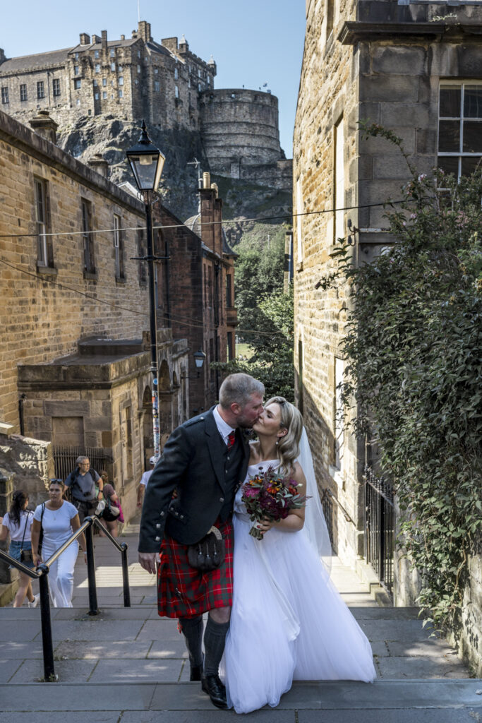 Edinburgh wedding photographer candid, a bride and groom standing on the Vennel steps having wedding photos.