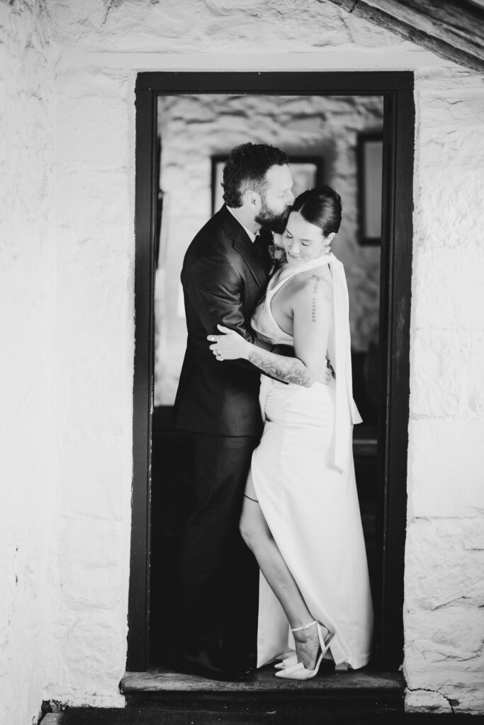 black and white image, bride and groom standing in a door way at Emu Bottom Homestead. Macedon Ranges wedding photography. Sunbury wedding photographer