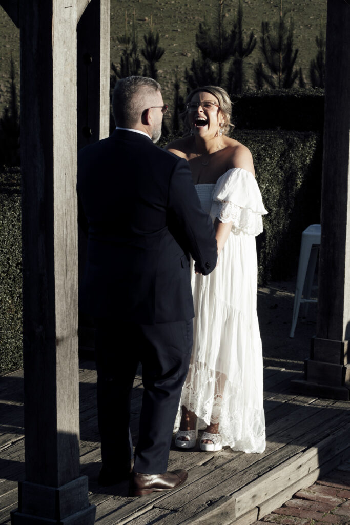 Warrawong estate wedding. Macedon Ranges Wedding photographer. Bride and Groom standing at alter laughing