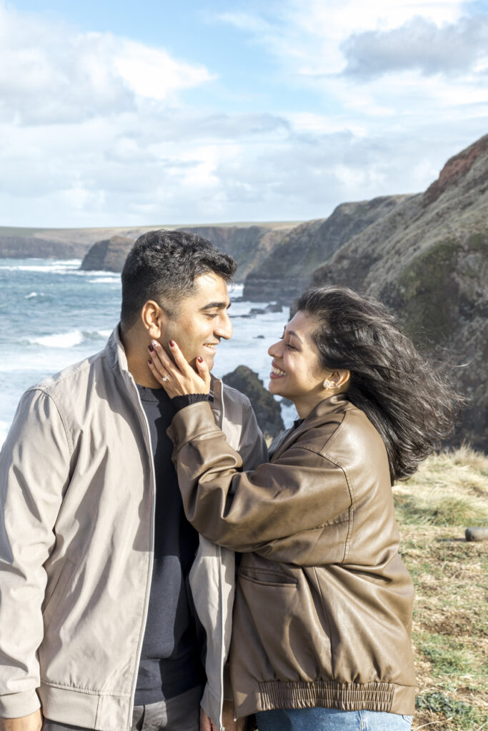 Melbourne Proposal Photography a couple getting engaged in Flinders. Young couple standing on cliff top laughing and looking at each other.