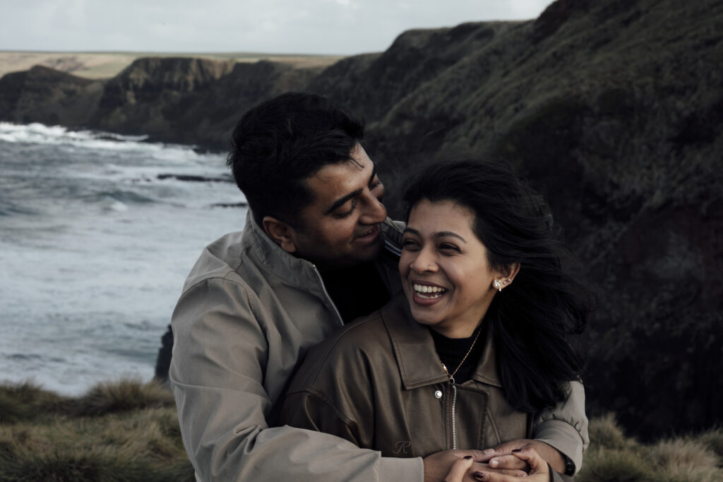 Melbourne Proposal Photography a couple getting engaged in Flinders. Young couple standing on cliff top laughing and looking at each other.