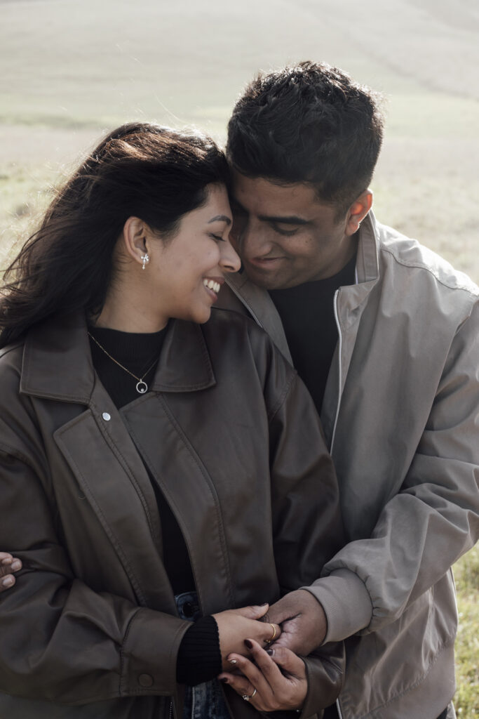 Melbourne Proposal Photography a couple getting engaged in Flinders. Young couple standing on cliff top laughing and holding hands