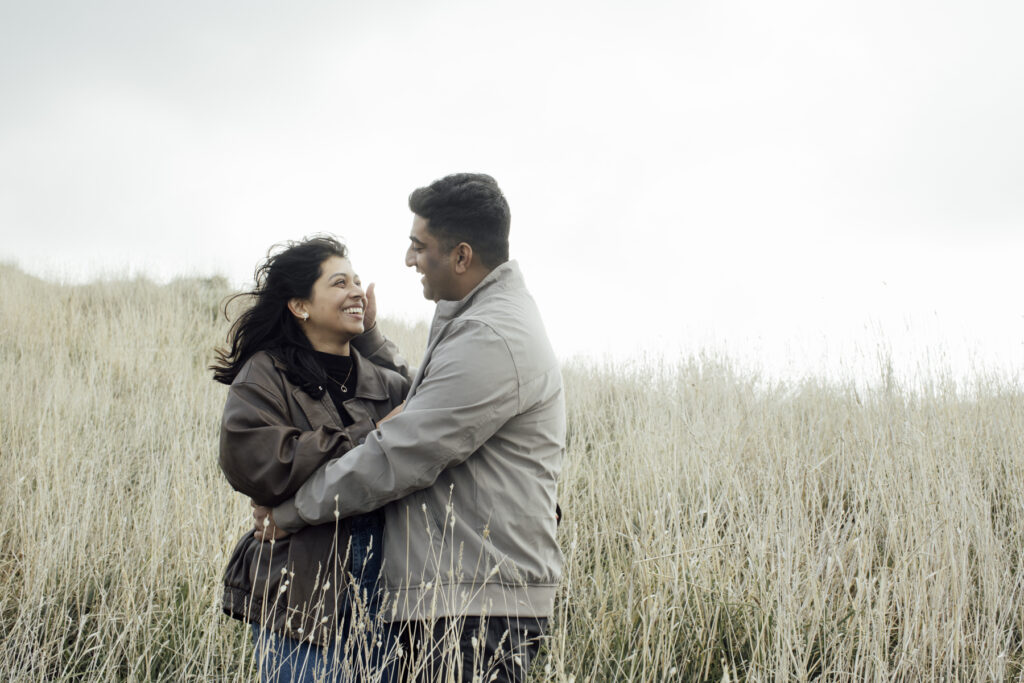 Melbourne Proposal Photography a couple getting engaged in Flinders. Young couple standing on cliff top laughing, holding hands and walking