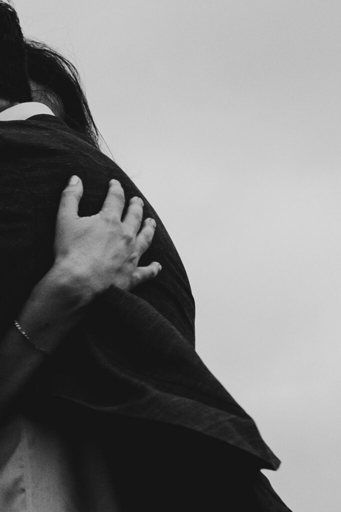 Black and white close up of hangs and hugging at Gurneys' Cider Wedding
