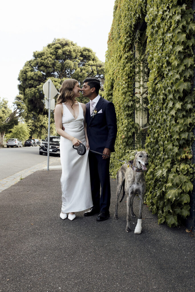A bride and groom having photos with dog. The village Grae in Kew in the courtyard. The Magic of a Wine Bar Wedding in Melbourne