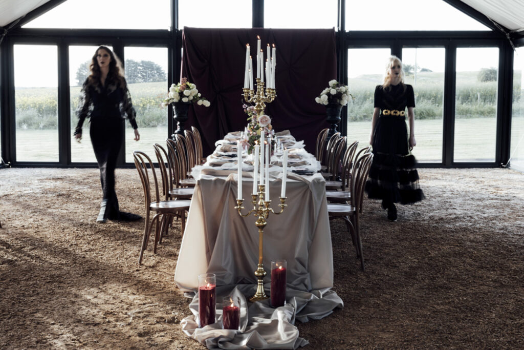 two women at a wedding in Scrub Hill, they are wearing black gowns by Gwendolyn Couture. They alos have incredible crowns by Stephanie Browne, the flowers are wild by Larkspur flowers. The setting is beautiful and summery.