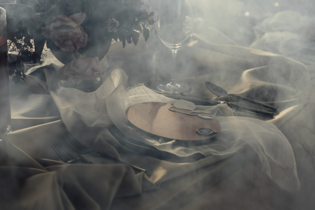 Wedding reception table setting at Scrub Hill, The table linen is silk and glowy golden, the flowers are soft and warm, candelabras line the table to give a moody vibe. The overall image is warm and lucious